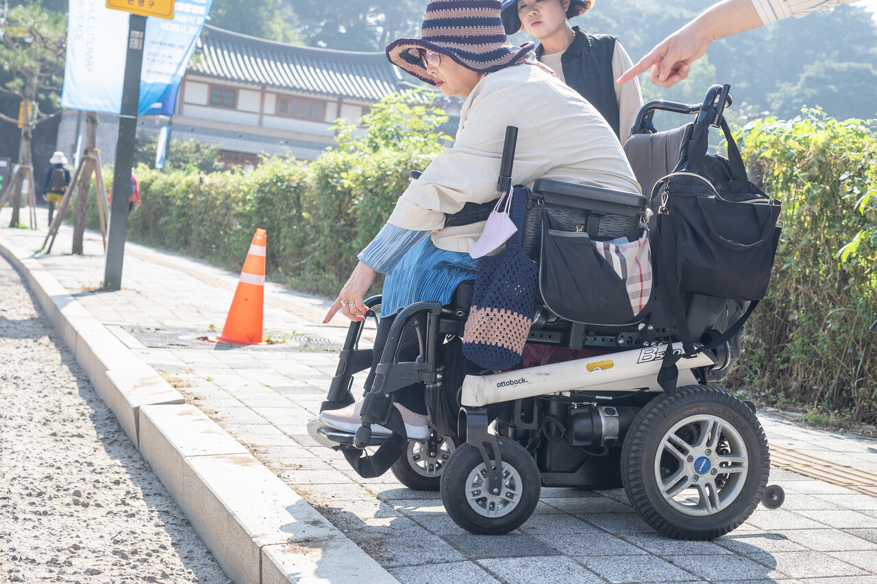 휠체어가 지나갈 수 없는 도로변 높은 턱을 가리키는 모습 (사진 : 김연웅 기자)