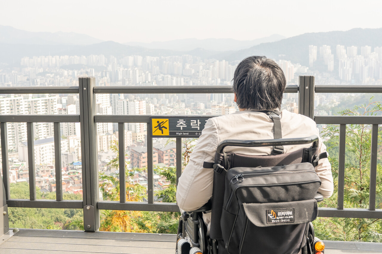 휠체어를 타고 전망대에서 도심을 내려다보는 모습 (사진 : 김연웅 기자)